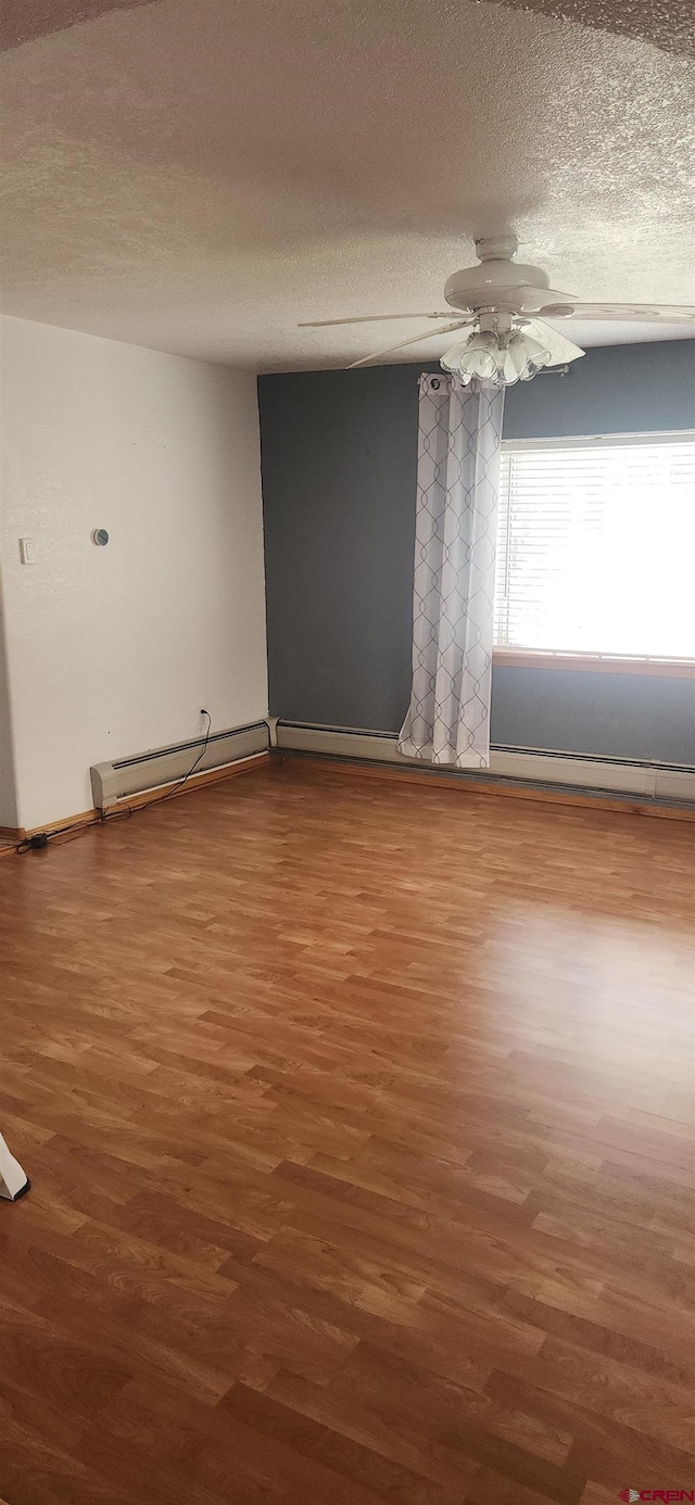 unfurnished room featuring ceiling fan, a textured ceiling, wood-type flooring, and a baseboard heating unit