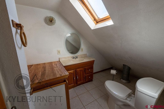 bathroom featuring vanity, vaulted ceiling with skylight, toilet, and tile patterned flooring