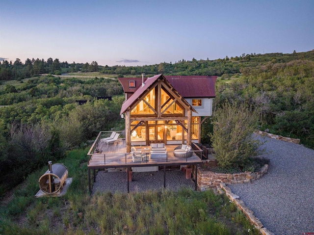 back house at dusk with outdoor lounge area and a deck