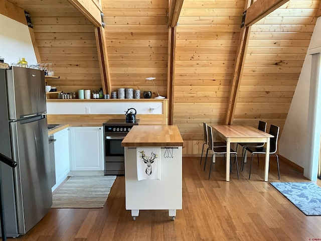 kitchen with beamed ceiling, white cabinets, wooden counters, light hardwood / wood-style floors, and appliances with stainless steel finishes