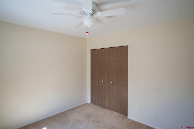 unfurnished bedroom featuring ceiling fan, a closet, and light carpet