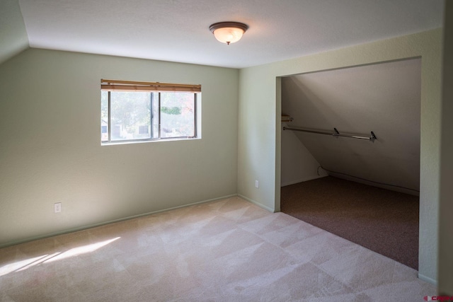 unfurnished bedroom with light carpet, lofted ceiling, and a closet