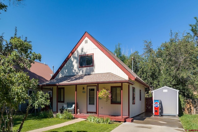 view of front of home with a front yard, a storage shed, and a porch