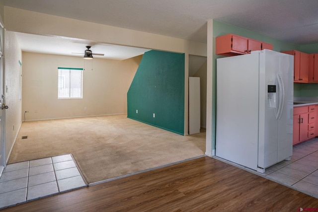 kitchen featuring ceiling fan, light carpet, and white fridge with ice dispenser