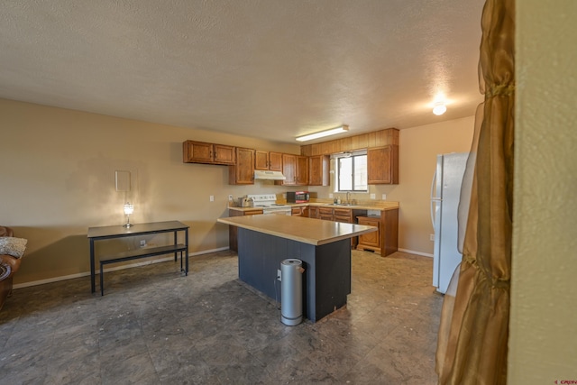 kitchen with a kitchen island, white appliances, sink, and a textured ceiling