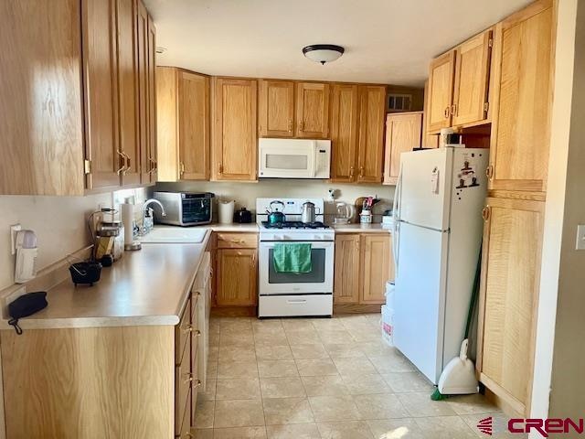 kitchen featuring white appliances, light countertops, and a sink