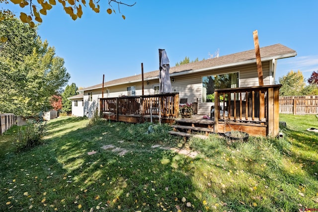 rear view of property featuring a wooden deck and a lawn