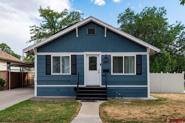 bungalow-style home with a front yard and a carport