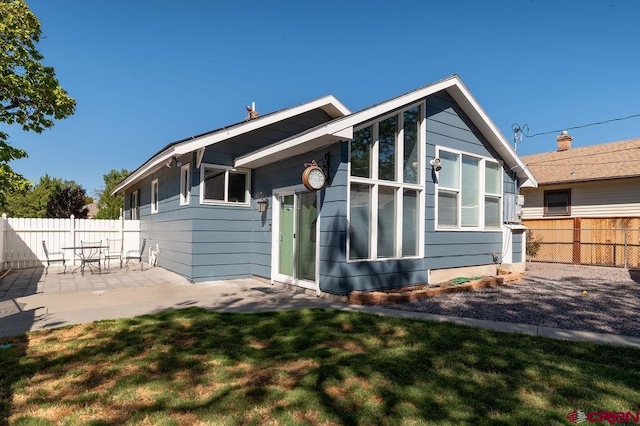 back of house with a patio and a lawn