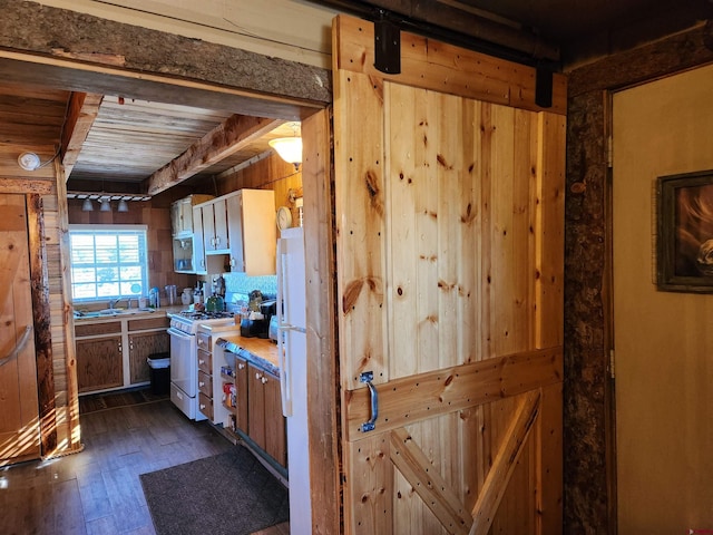 kitchen featuring sink, wooden walls, white gas stove, and dark hardwood / wood-style flooring