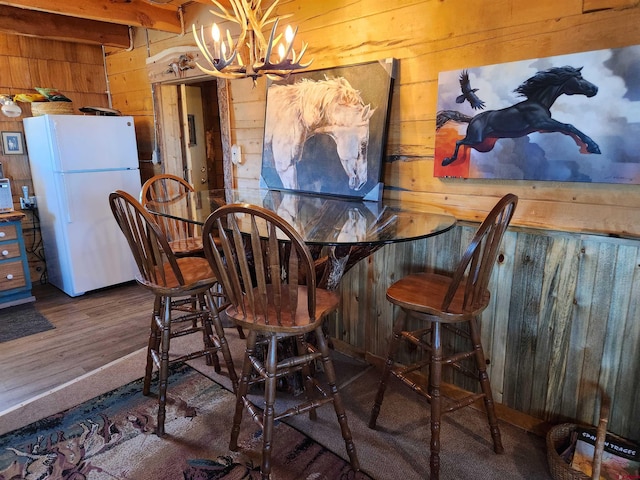 dining space with wood walls, dark hardwood / wood-style floors, and a chandelier