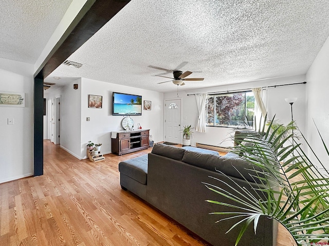 living room featuring ceiling fan, light hardwood / wood-style floors, and a textured ceiling