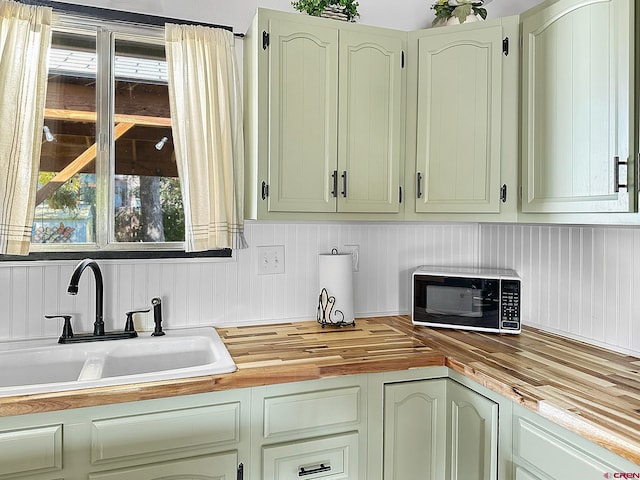 kitchen with butcher block countertops, green cabinets, and sink