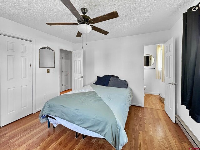 bedroom featuring ensuite bathroom, ceiling fan, a baseboard radiator, hardwood / wood-style flooring, and a textured ceiling