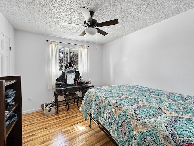 bedroom with ceiling fan, hardwood / wood-style floors, and a textured ceiling