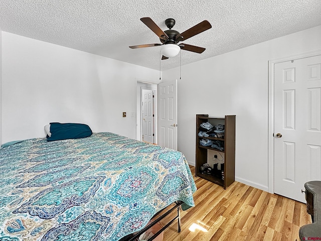 bedroom featuring ceiling fan, hardwood / wood-style flooring, and a textured ceiling