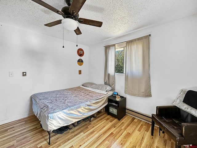 bedroom with ceiling fan, a baseboard radiator, wood-type flooring, and a textured ceiling