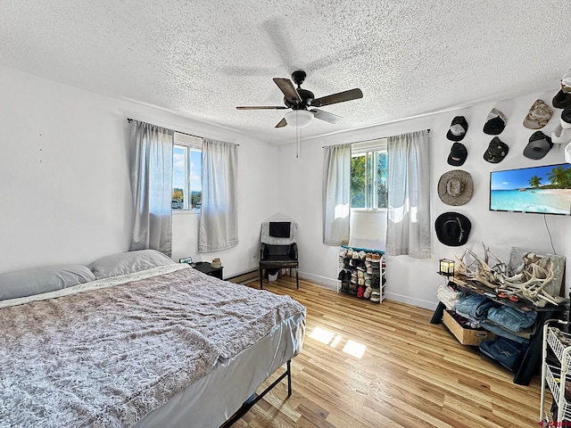 bedroom featuring ceiling fan, hardwood / wood-style floors, and a textured ceiling