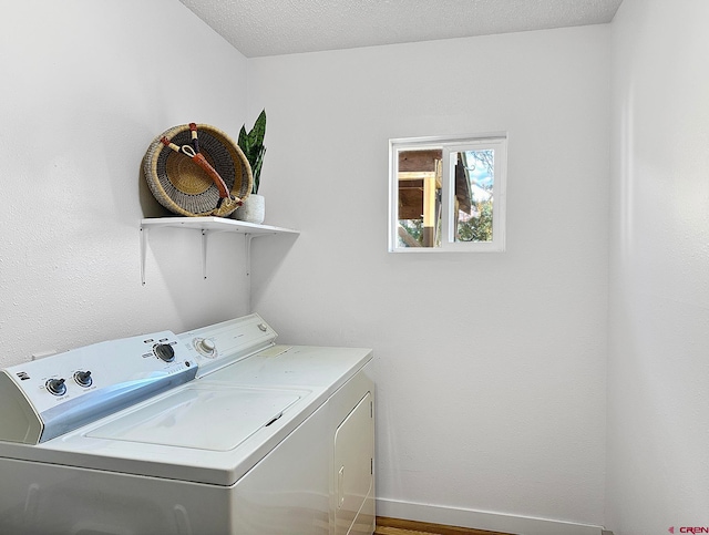 laundry room with wood-type flooring, a textured ceiling, and washing machine and dryer