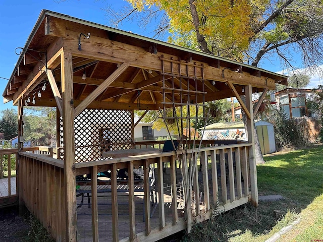 wooden terrace with a gazebo, a lawn, and a shed