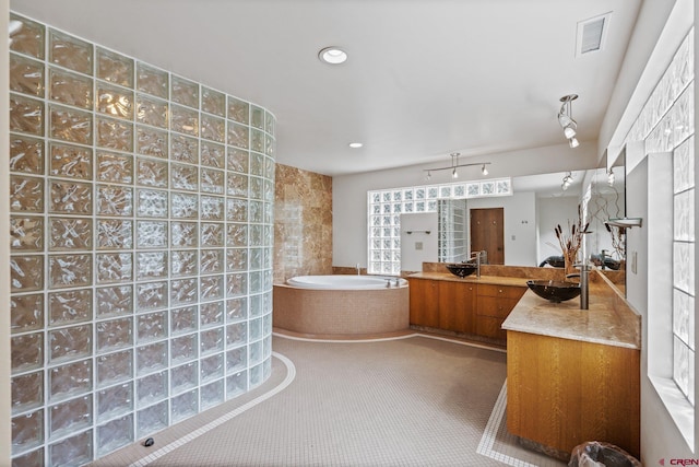 bathroom featuring vanity and tiled bath