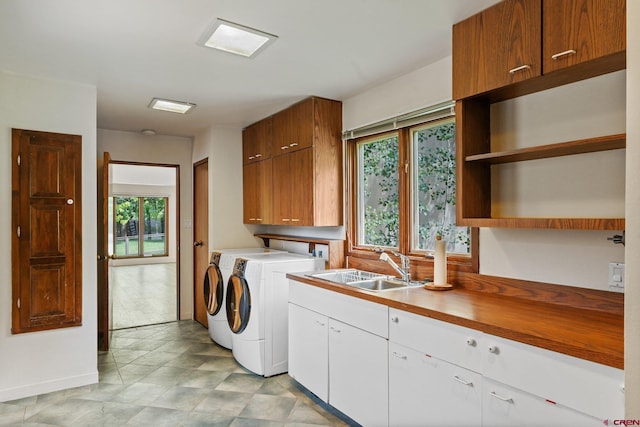 clothes washing area featuring washer and clothes dryer, cabinets, and sink