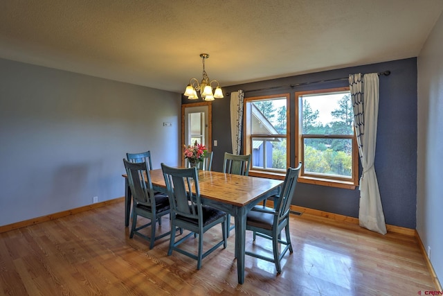 dining room featuring a notable chandelier, light hardwood / wood-style floors, and a textured ceiling