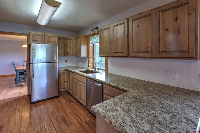 kitchen with stainless steel appliances, stone counters, sink, and dark hardwood / wood-style flooring