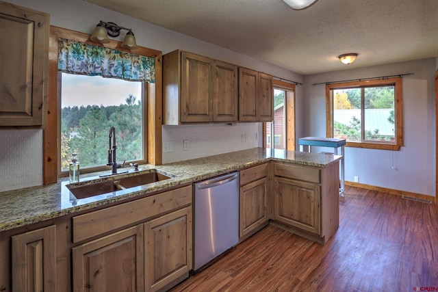 kitchen featuring light stone counters, sink, kitchen peninsula, stainless steel dishwasher, and dark hardwood / wood-style floors