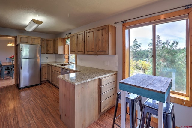 kitchen featuring stainless steel refrigerator, dark hardwood / wood-style flooring, sink, light stone countertops, and a textured ceiling