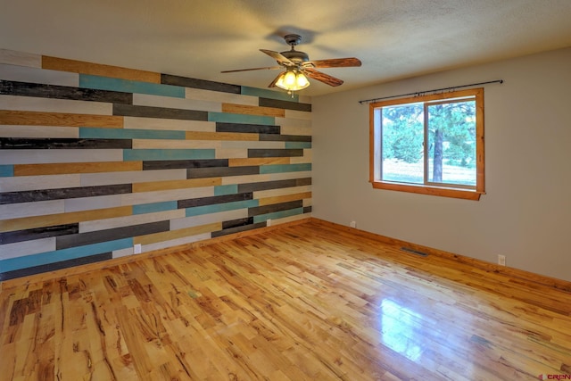 empty room featuring light hardwood / wood-style flooring, a textured ceiling, and ceiling fan