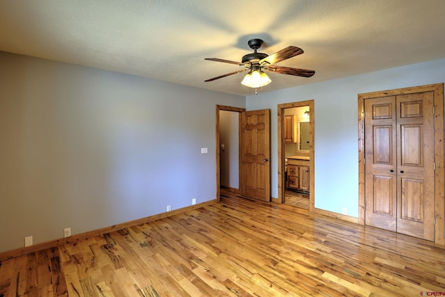 unfurnished bedroom featuring ceiling fan, a textured ceiling, light wood-type flooring, and connected bathroom