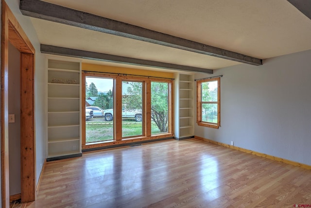 spare room with light hardwood / wood-style floors and beamed ceiling