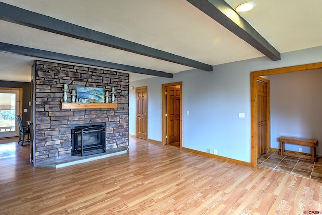 unfurnished living room featuring beamed ceiling and light hardwood / wood-style flooring