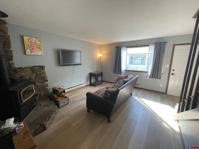 living room with a baseboard radiator, light hardwood / wood-style flooring, and a wood stove