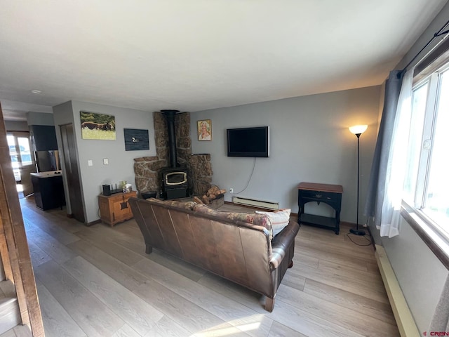 living room featuring a wood stove, plenty of natural light, and light hardwood / wood-style floors