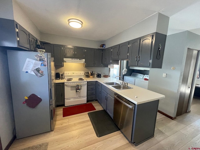 kitchen with independent washer and dryer, stainless steel appliances, sink, light hardwood / wood-style floors, and gray cabinets