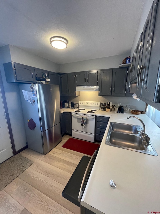 kitchen featuring sink, a textured ceiling, stainless steel refrigerator, white range with electric cooktop, and light wood-type flooring