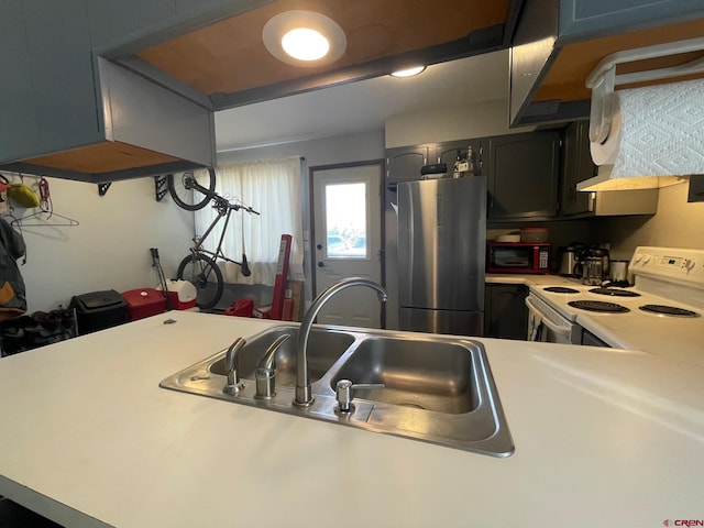 kitchen featuring white electric range oven, stainless steel fridge, and sink