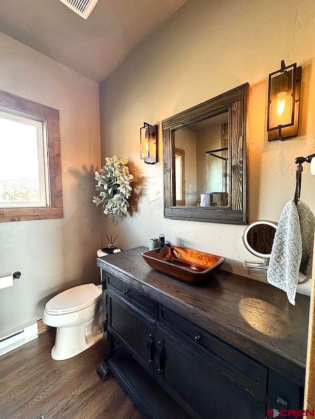 bathroom with baseboard heating, hardwood / wood-style flooring, vanity, and toilet