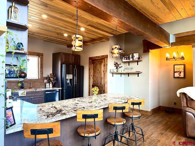 kitchen featuring pendant lighting, dark wood-type flooring, black refrigerator with ice dispenser, wood ceiling, and a kitchen bar