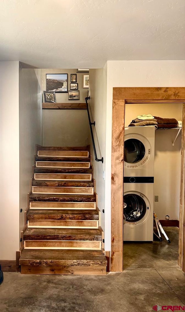 stairway with stacked washing maching and dryer and concrete floors