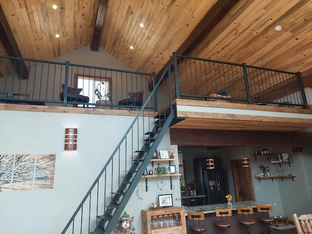 staircase with high vaulted ceiling, beam ceiling, and wooden ceiling