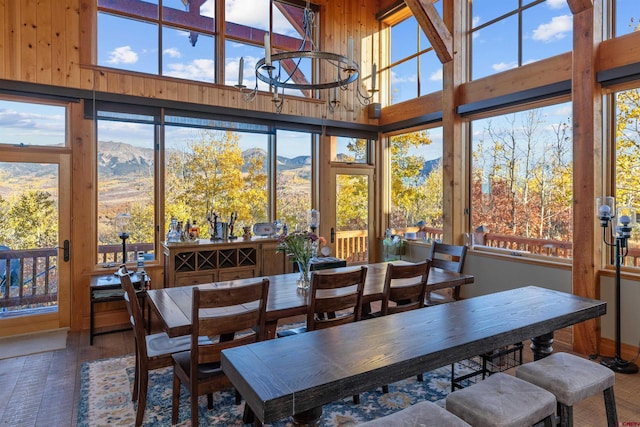 dining area featuring a mountain view, hardwood / wood-style flooring, a towering ceiling, and a chandelier