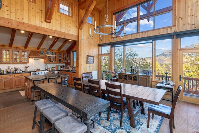 dining space featuring high vaulted ceiling, sink, a mountain view, beam ceiling, and wood walls