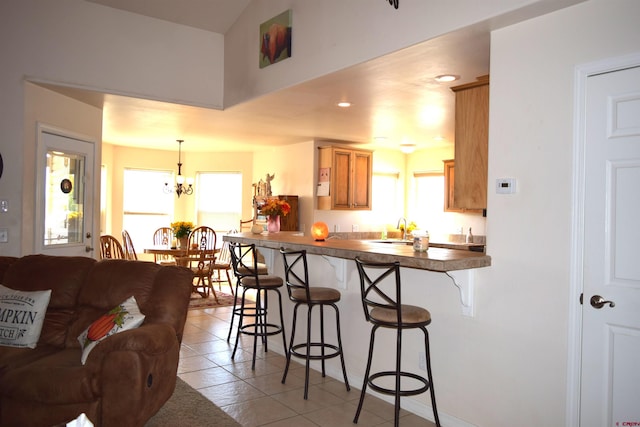 kitchen with a breakfast bar area, decorative light fixtures, sink, kitchen peninsula, and light tile patterned floors