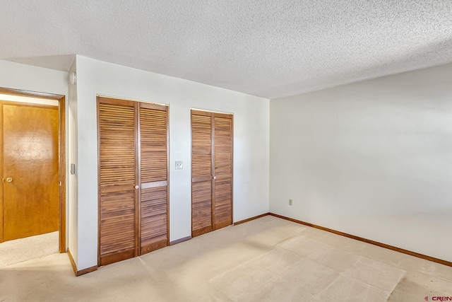 unfurnished bedroom featuring a textured ceiling and two closets