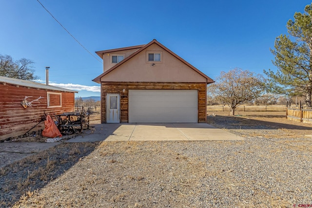 exterior space with an outbuilding, a rural view, and a garage