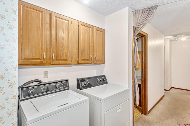 laundry area featuring light carpet, washer and clothes dryer, cabinets, and a textured ceiling