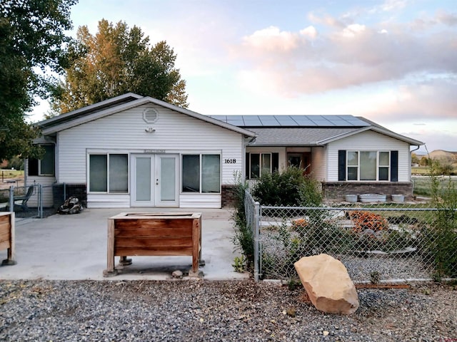 back house at dusk featuring a patio area and solar panels